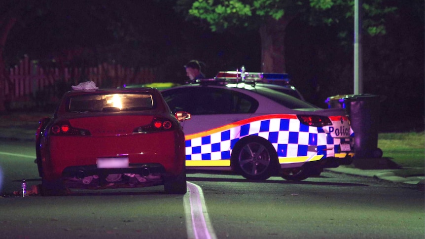 Night shot of a red car next to a police car where pedestrians were mown down in Canning Vale.