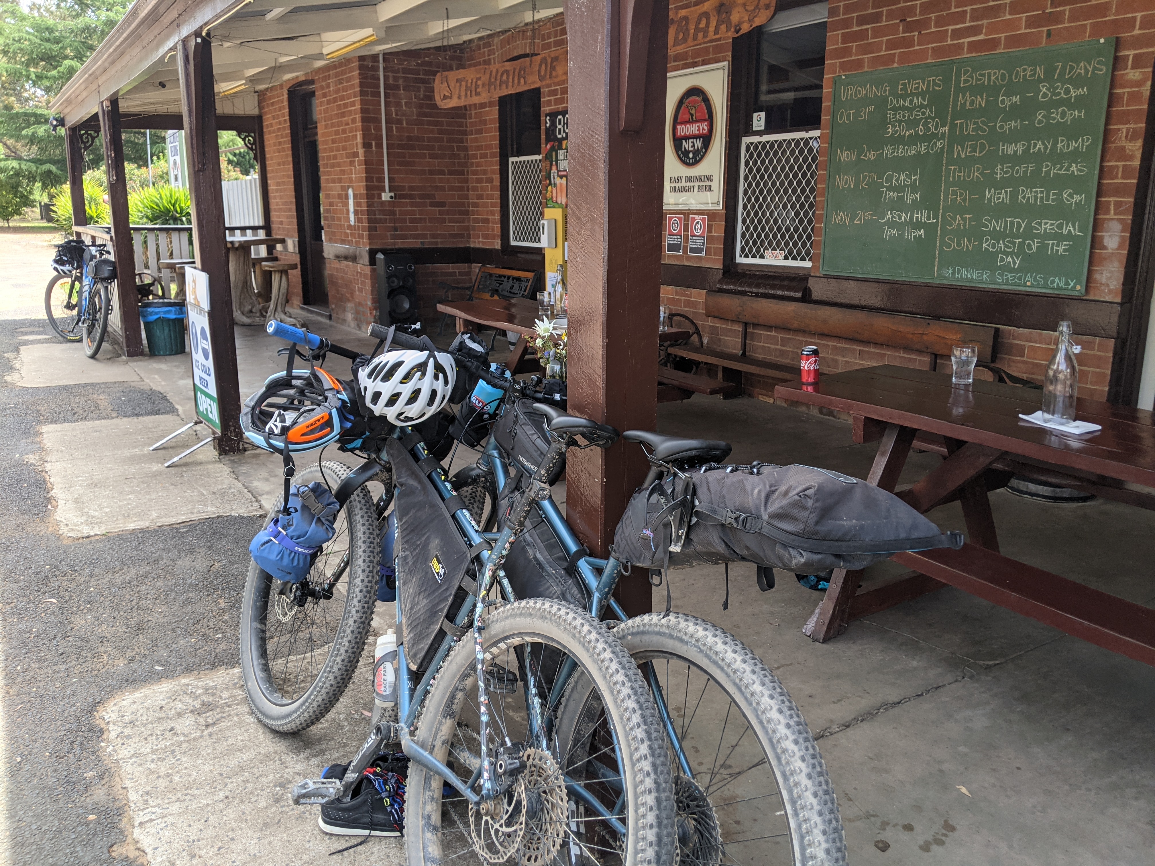 Two bikes are propped up against a post outside a pub entrance.