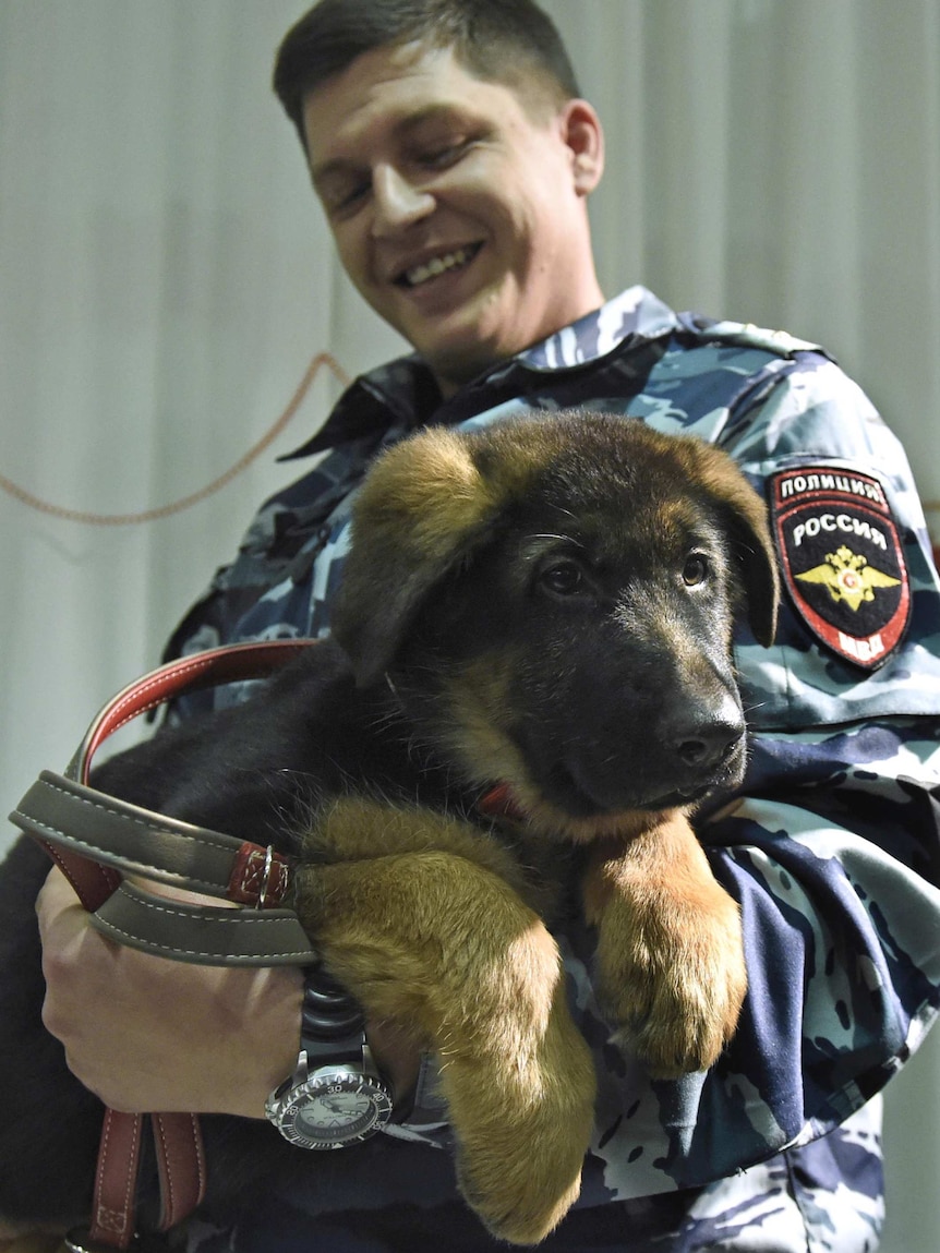 A Russian police officer holds France's new puppy