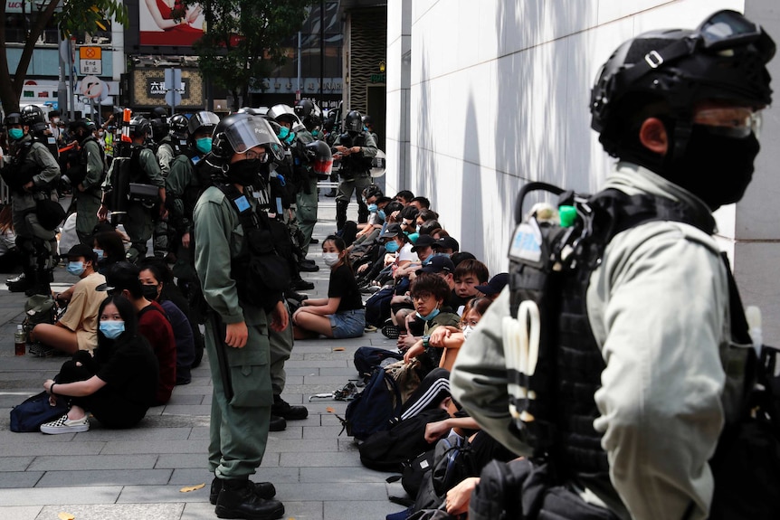 Pro-democracy protesters sit as they were detained by riot police.
