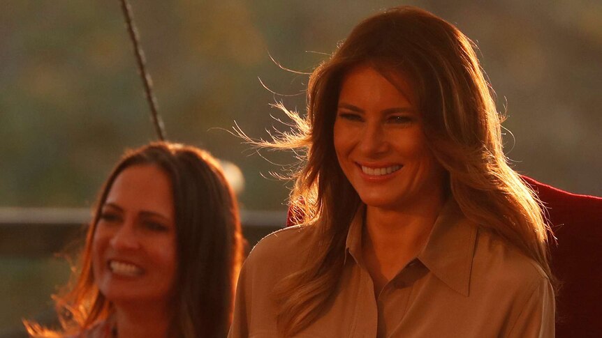 Melania Trump sits next to her Communications Director Stephanie Grisham in orange lighting.