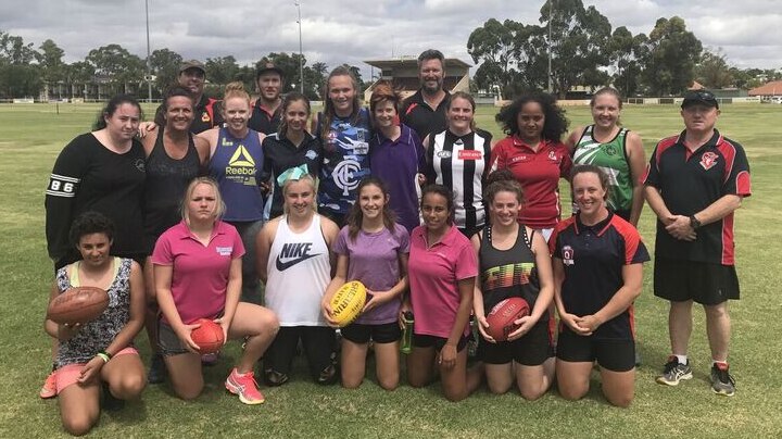 Women line up holding footballs at the Berri Football Oval.