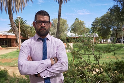 A man stands with his arms crossed looking serious.