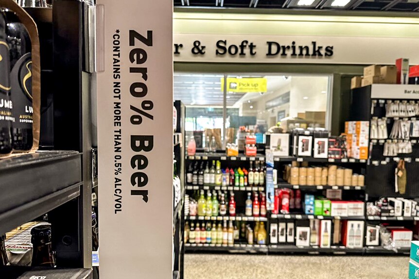 A sign in a Dan Murphy's liquor store aisle that reads Zero % Beer. An array of colourful bottles are in the background
