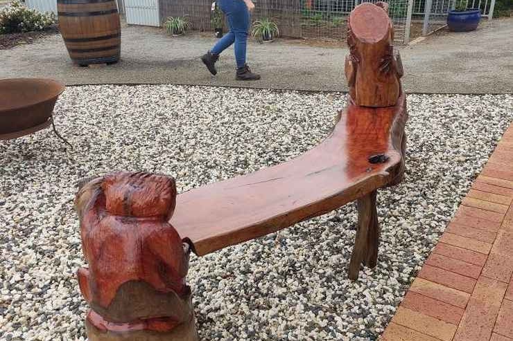 A wooden bench with a koala engraved at each end. 