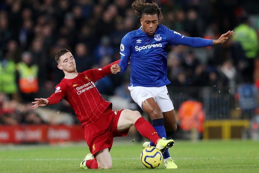 Andy Robertson slides in on Alex Iwobi from behind and wins the ball