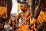 A young Aboriginal boy dances, his body is decorated with traditional pigment markings.