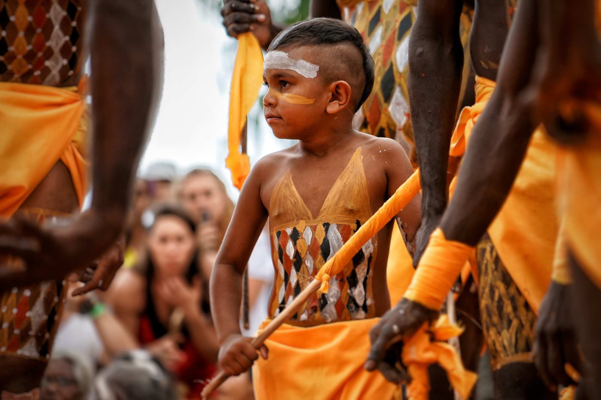 一个年轻的土著男孩跳舞，他的身体装饰着传统的颜料标记。