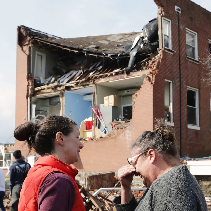 A woman wipes tears as she views the damage to a church