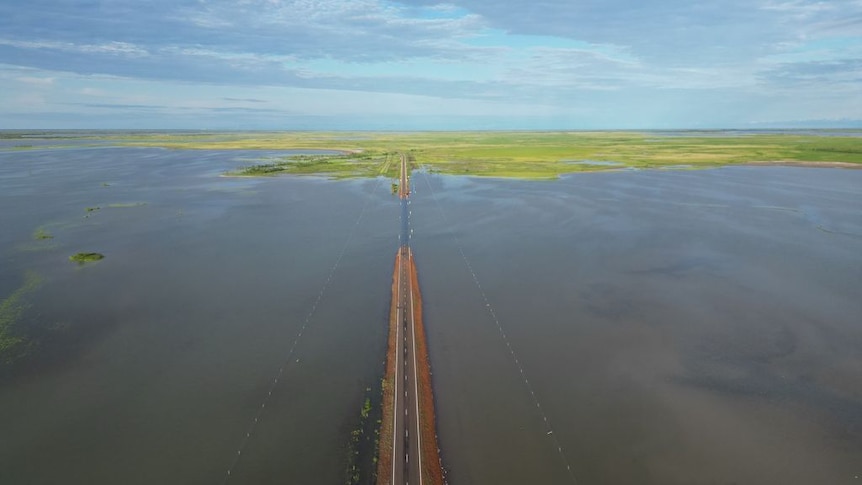 An aerial shot shows a vast body of floodwater over a country road