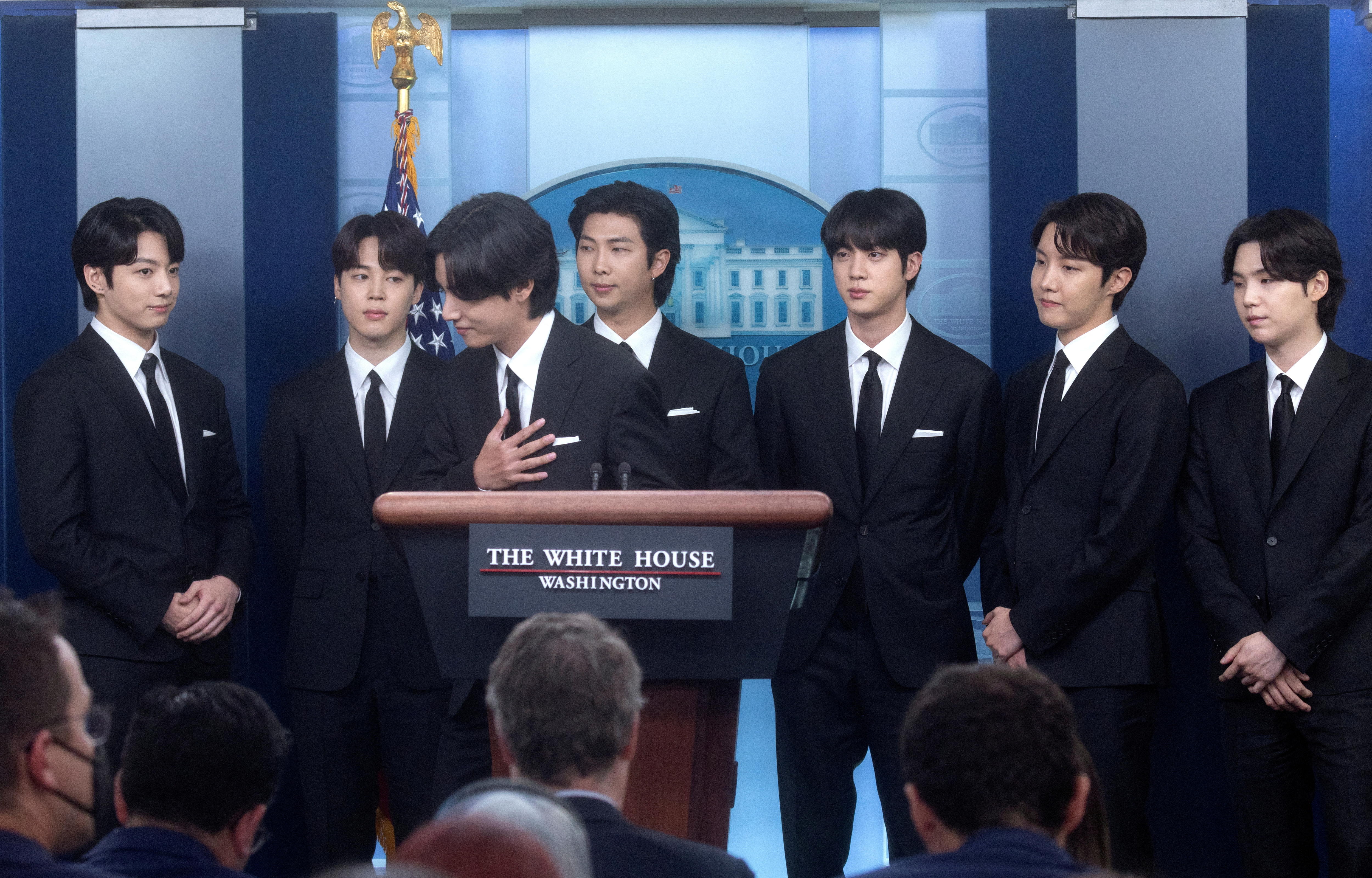 穿着西装的 BTS 成员站在白宫讲台后面。