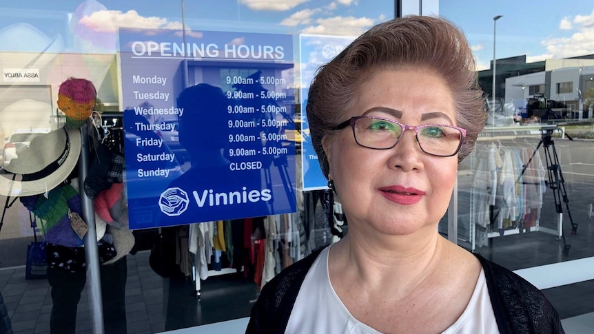 Woman stands in front of glass window of Vinnies store