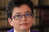 A  woman with short black hair and glasses
