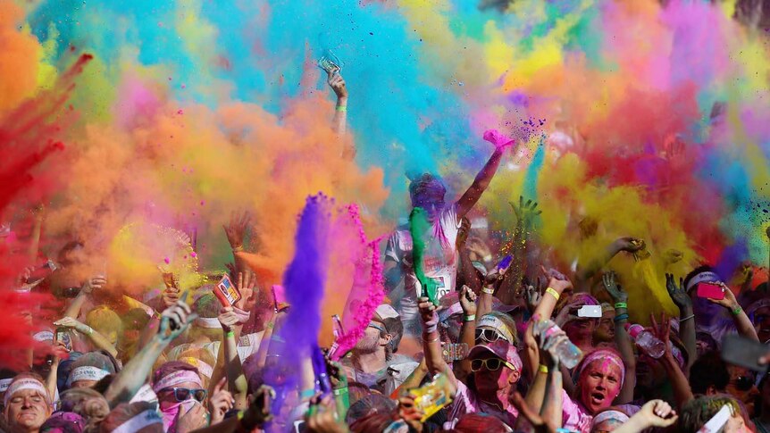 Runners celebrate and throw coloured powder on the Gold Coast