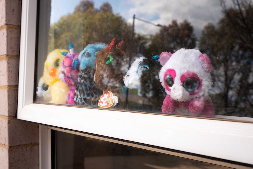 A line of teddy bears in a window.