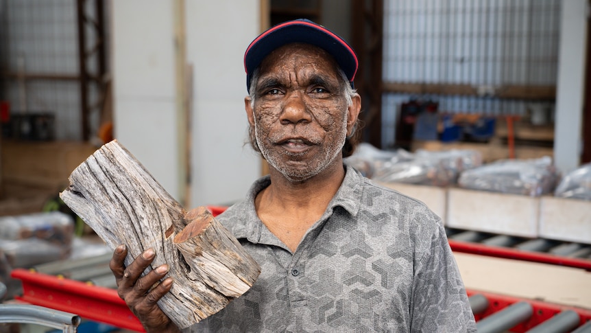 Erwin Mungee holding a piece of firewood