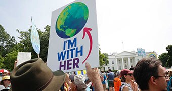 Protester holds sign during climate rally. It shows a globe with words 'I'm with her'