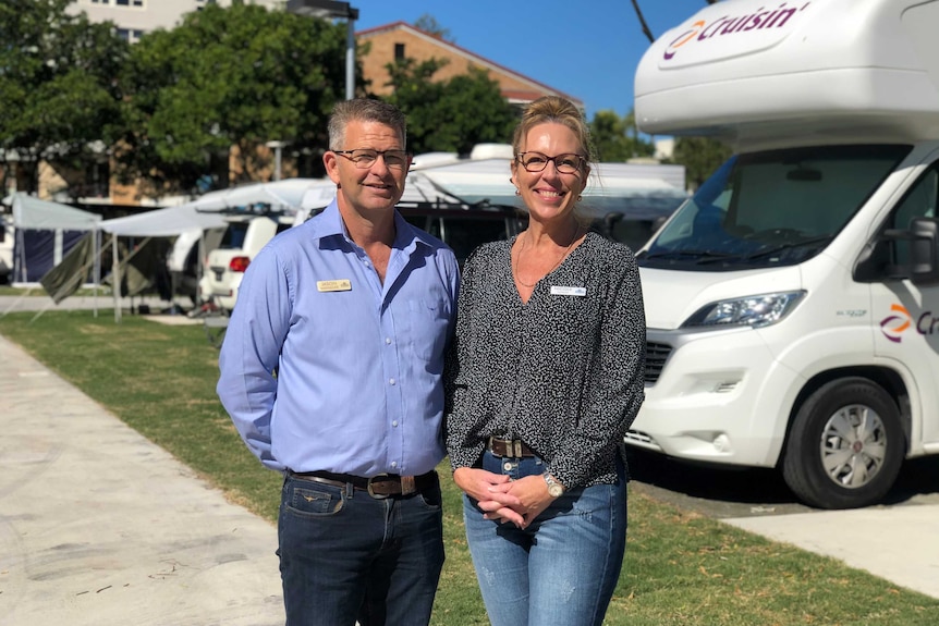 A couple smiling in front of caravans at a holiday park