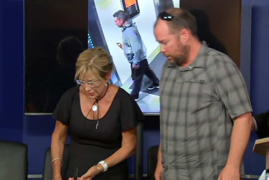 A woman and man are directed towards chairs by a detective from Victoria Police.