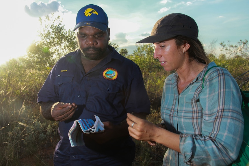 A man and a woman hold small lizards.