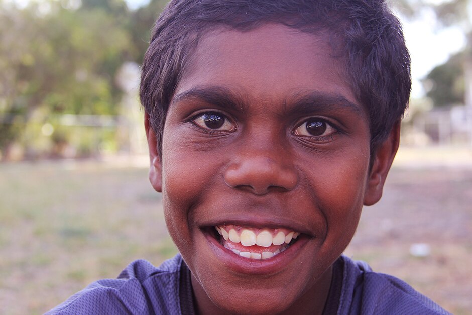 A young Aboriginal boy looks directly at the camera