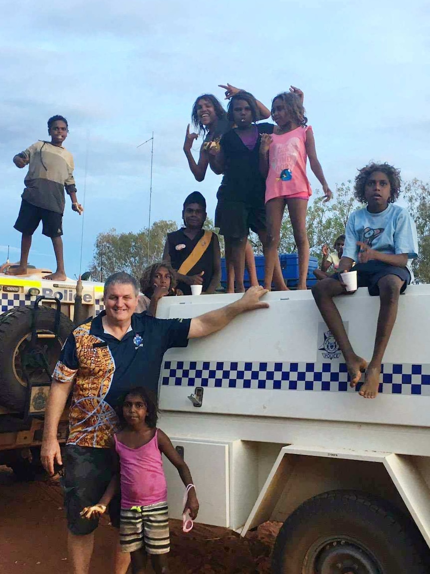 Don Couper standing in front of a 4WD vehicle with children standing around and on top of the car
