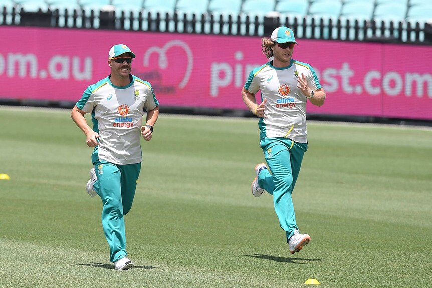 Two Australian cricketers jog together on the SCG during a team session ahead of a Test match.