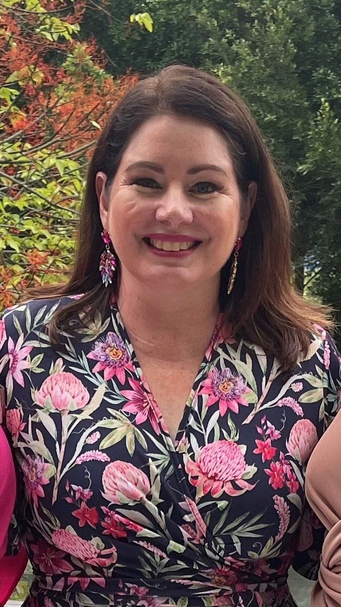 A smiling woman in a floral dress. 