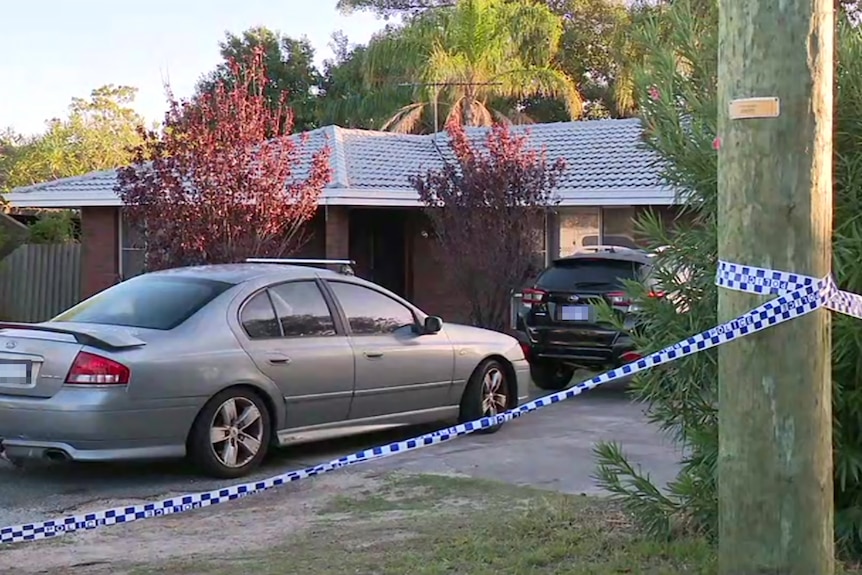 Police tape wrapped around a telephone pole outside a suburban house, with a silver sedan and black 4WD in the driveway.