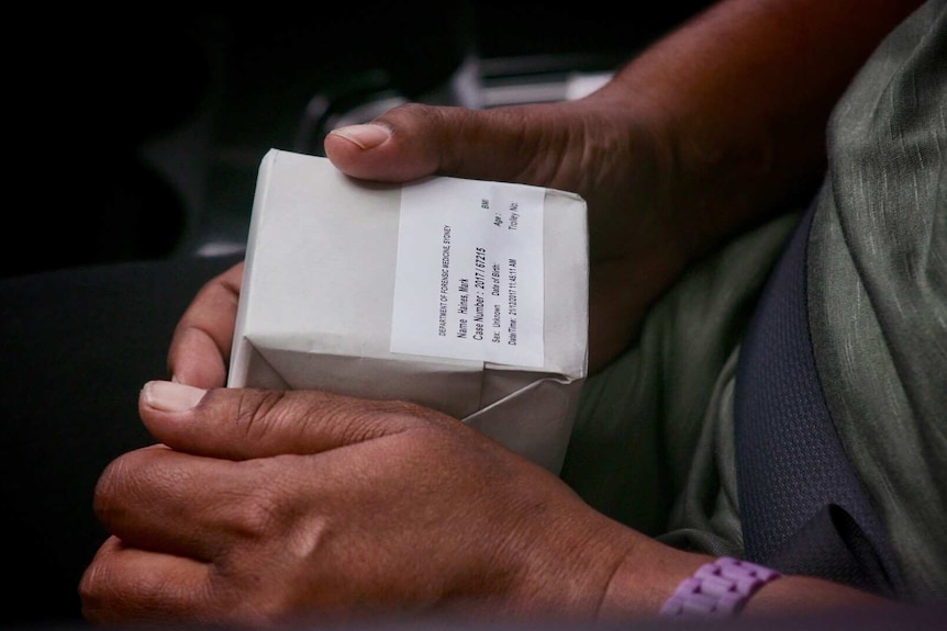 Two hands hold a small white package with a label on the front.