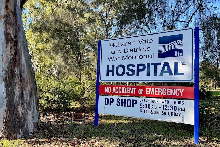 A sign stands at the start of a gum tree lined driveway to the hospital