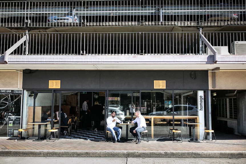 Two guys sit beneath a car park in Parramatta on a quiet street