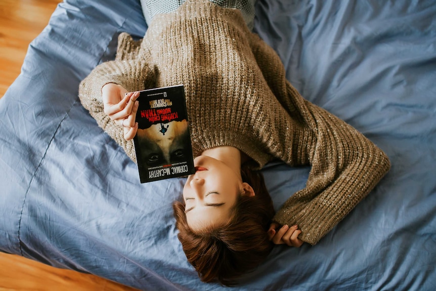 Woman lying in bed reading a book