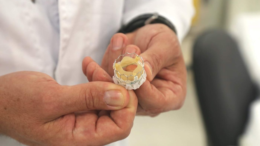 A man holds an artificial heart valve.