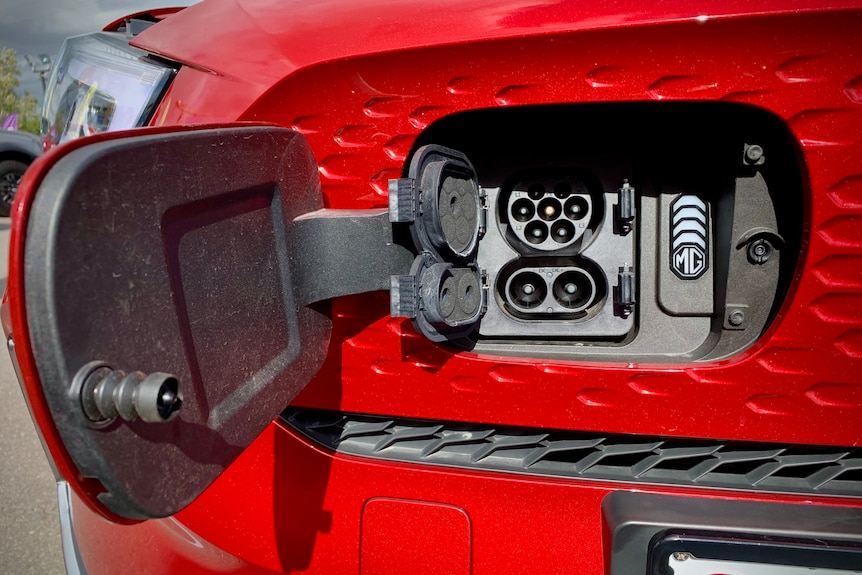 The red electric vehicle features a charging port behind a small door