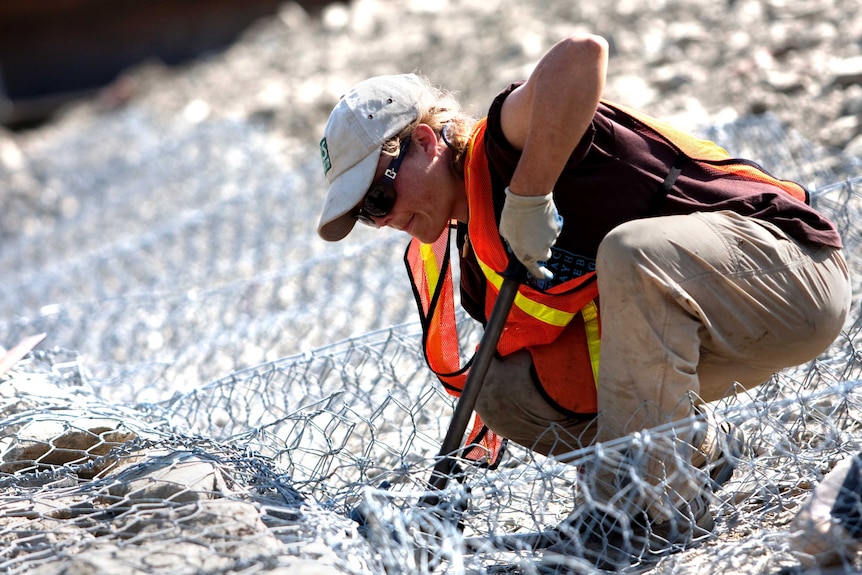 Female construction worker cuts fencing