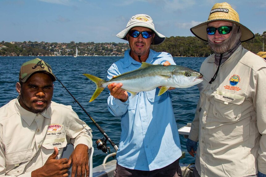 Three fishermen display a caught fish in Middle Harbour, Sydney.