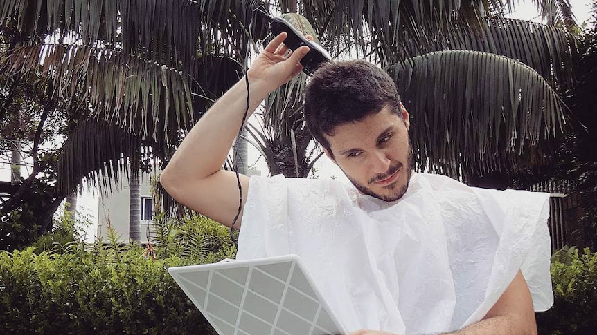 A man cutting his own hair with clippers.