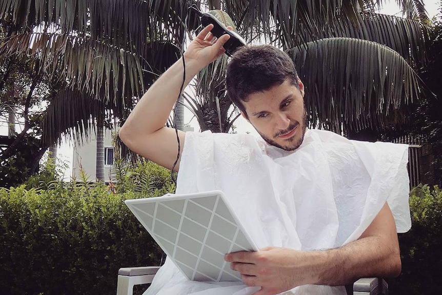 A man cutting his own hair with clippers.