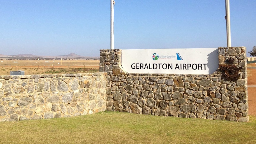 A wide shot of the sign at the entrance to Geraldton Airport with Australian and WA flags flying above.