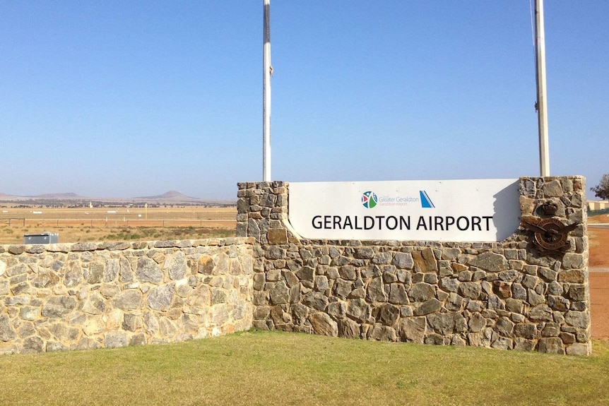 Un plan large du panneau à l'entrée de l'aéroport de Geraldton avec des drapeaux australiens et WA volant au-dessus.