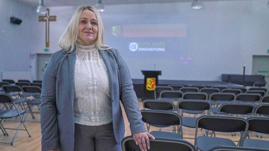 Anti-knife crime campaigner Alison Cope stands in a school auditorium lined with chairs.