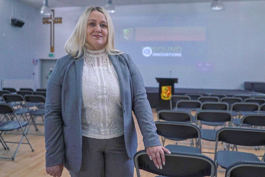 Anti-knife crime campaigner Alison Cope stands in a school auditorium lined with chairs.