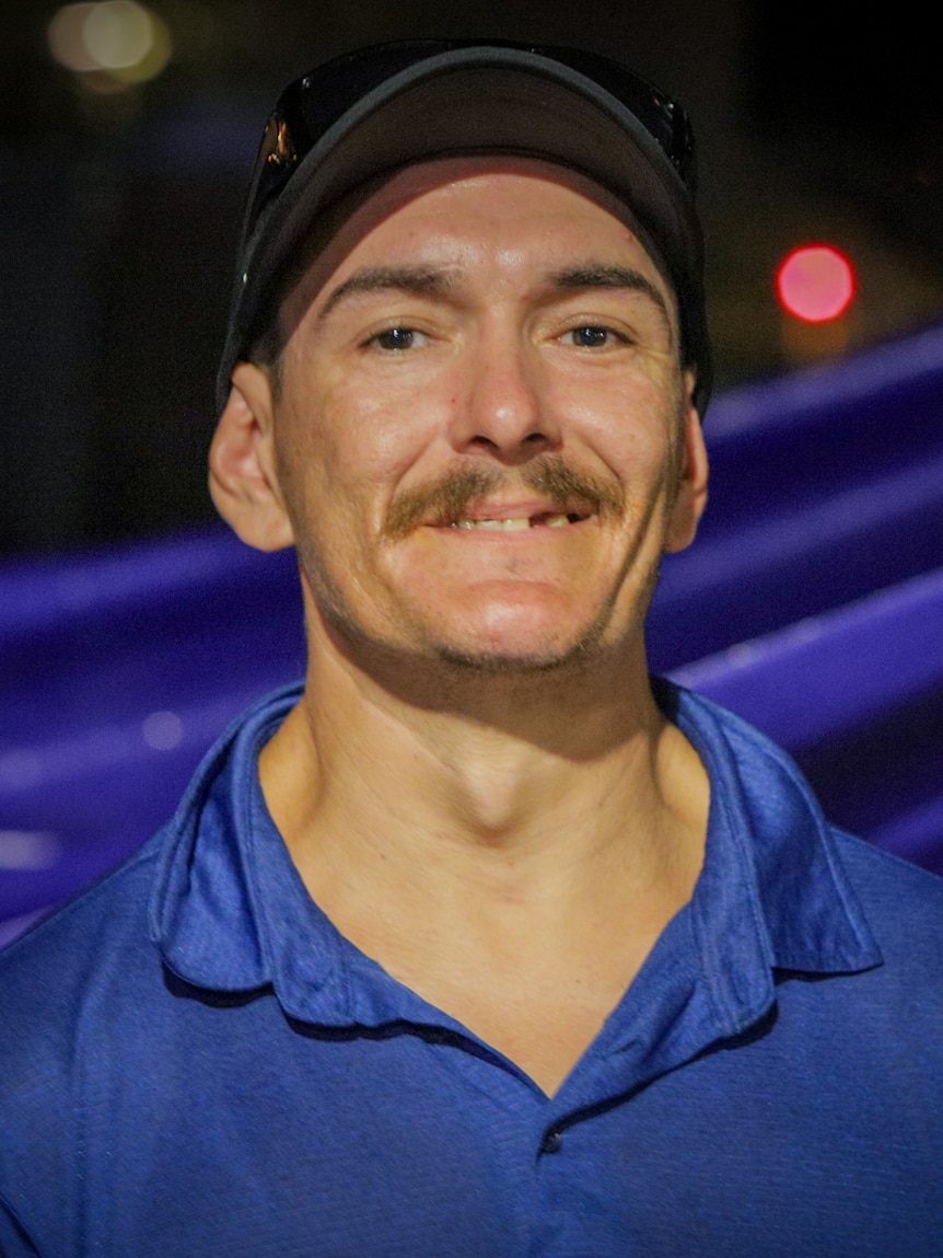 Man wearing a blue shirt and a black cap.