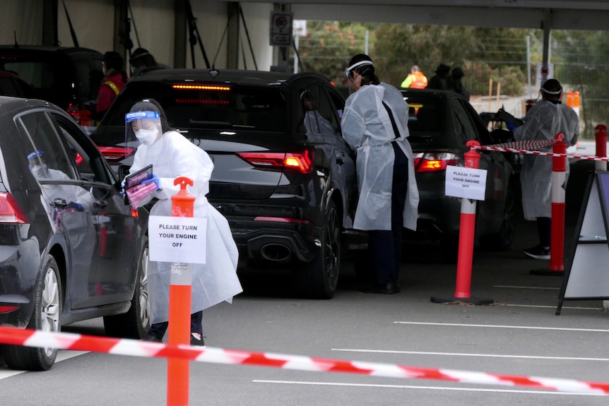 Nurses in PPE administer COVID-19 tests at a drive through testing clinic