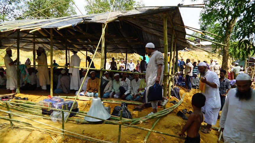 Men gather in and around a makeshift structure that will become a mosque.