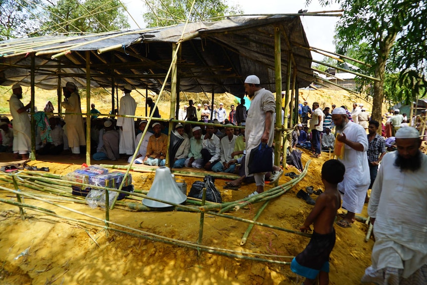 Men gather in and around a makeshift structure that will become a mosque.