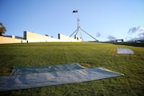 Tarps cover the vandalised grass.