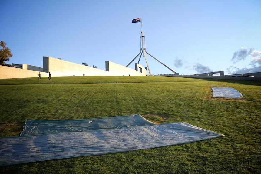 Tarps cover the vandalised grass.