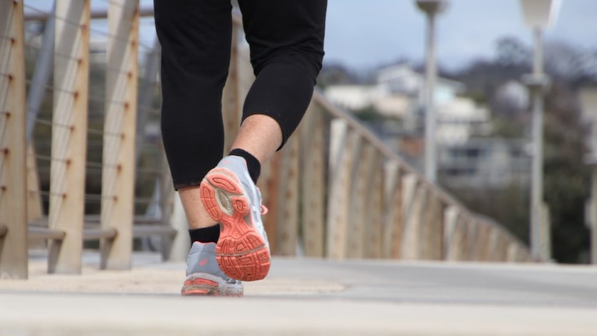 A close-up of feet walking on a footpath.